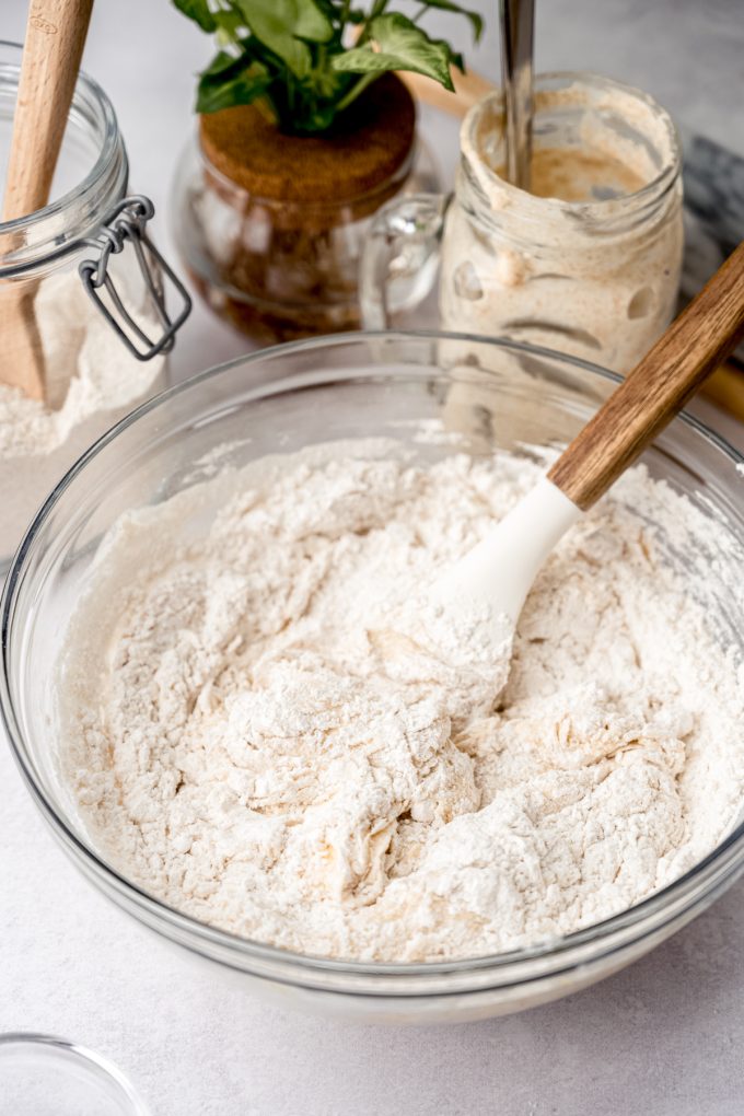 A bowl of sourdough cinnamon roll dough coming together in a bowl with a spatula.