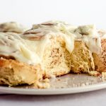 sourdough cinnamon rolls on a plate with drippy cream cheese frosting