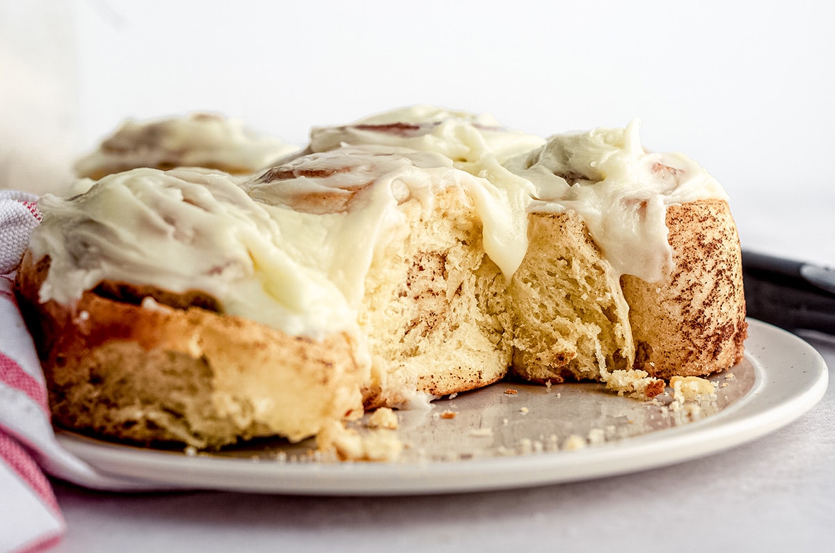 sourdough cinnamon rolls on a plate with drippy cream cheese frosting