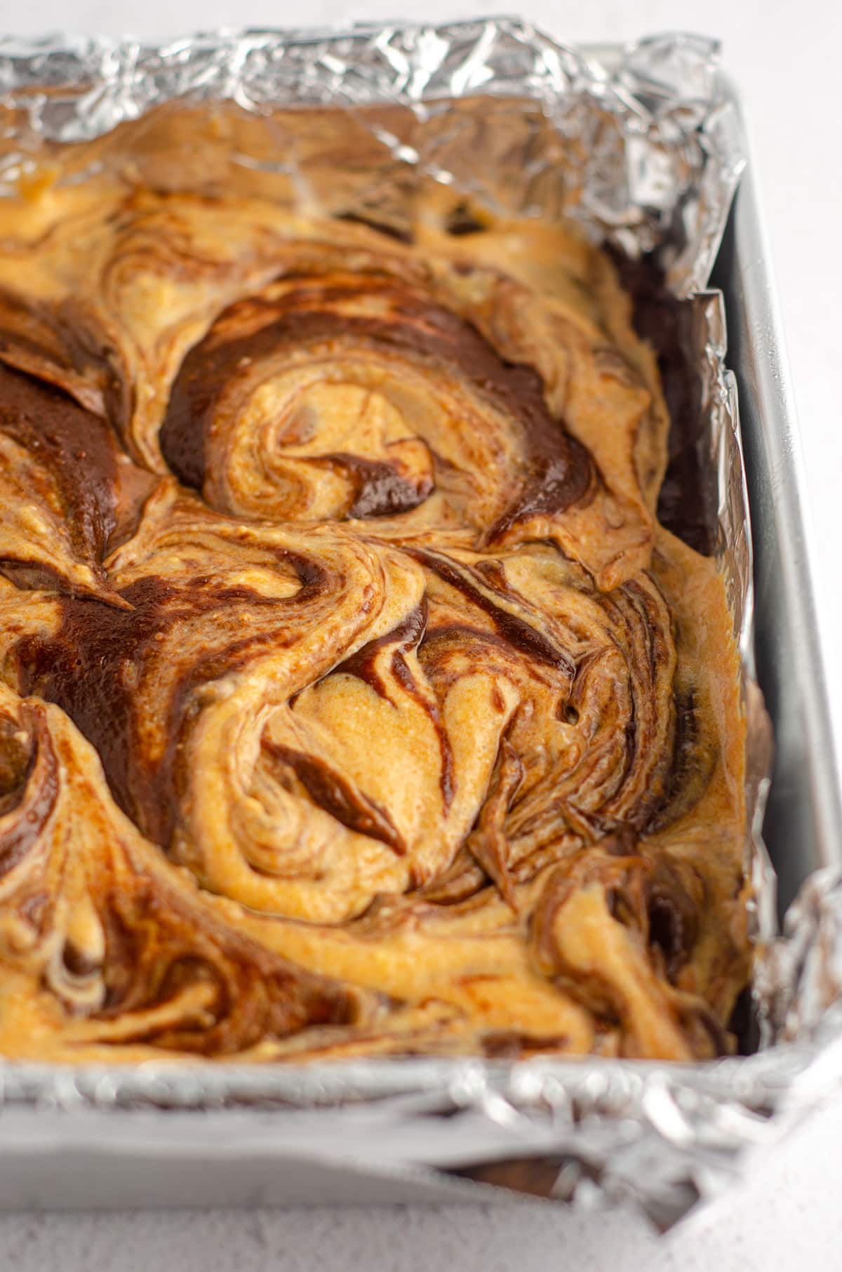 pumpkin cheesecake brownies in a pan ready to bake