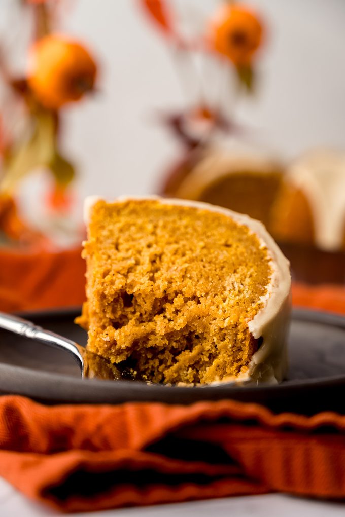 A slice of pumpkin Bundt cake on a plate with a fork and a bite taken out of it.