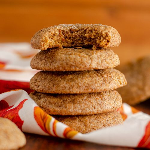 stack of pumpkin spice cookies with a bite taken out of the top cookie