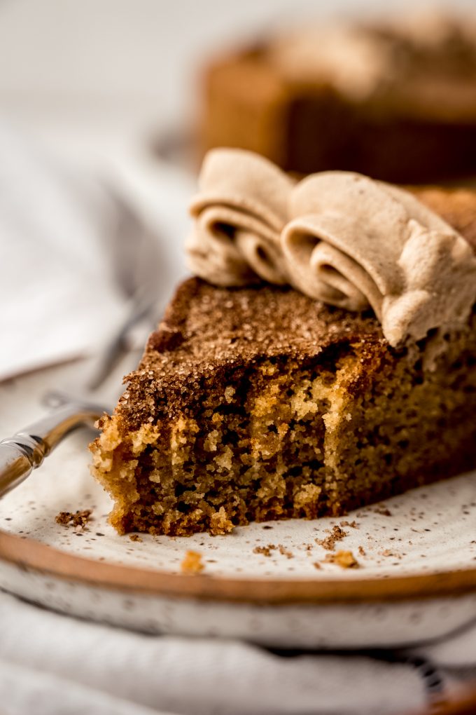 A photo of a slice of snickerdoodle cookie cake on a plate with a fork and a bite taken out of it.