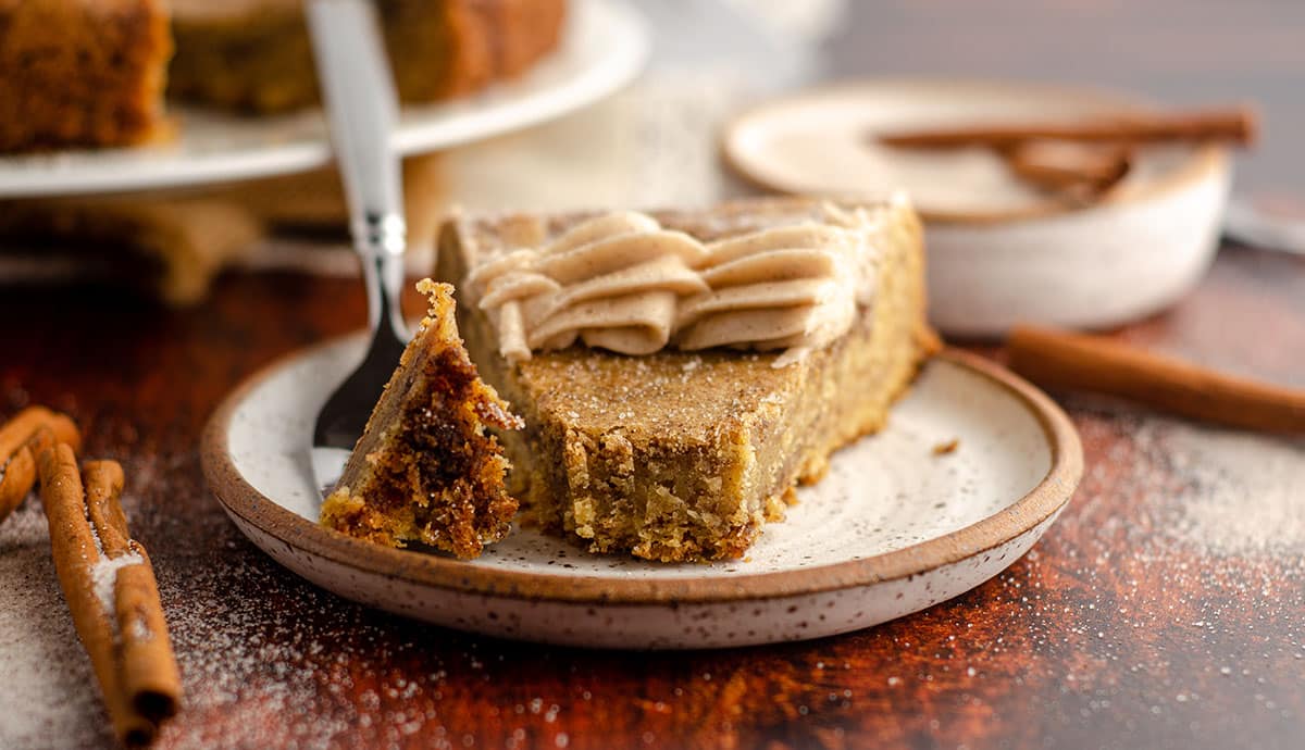 snickerdoodle cookie cake sitting on a ceramic plate with a bite taken out and sitting on a fork