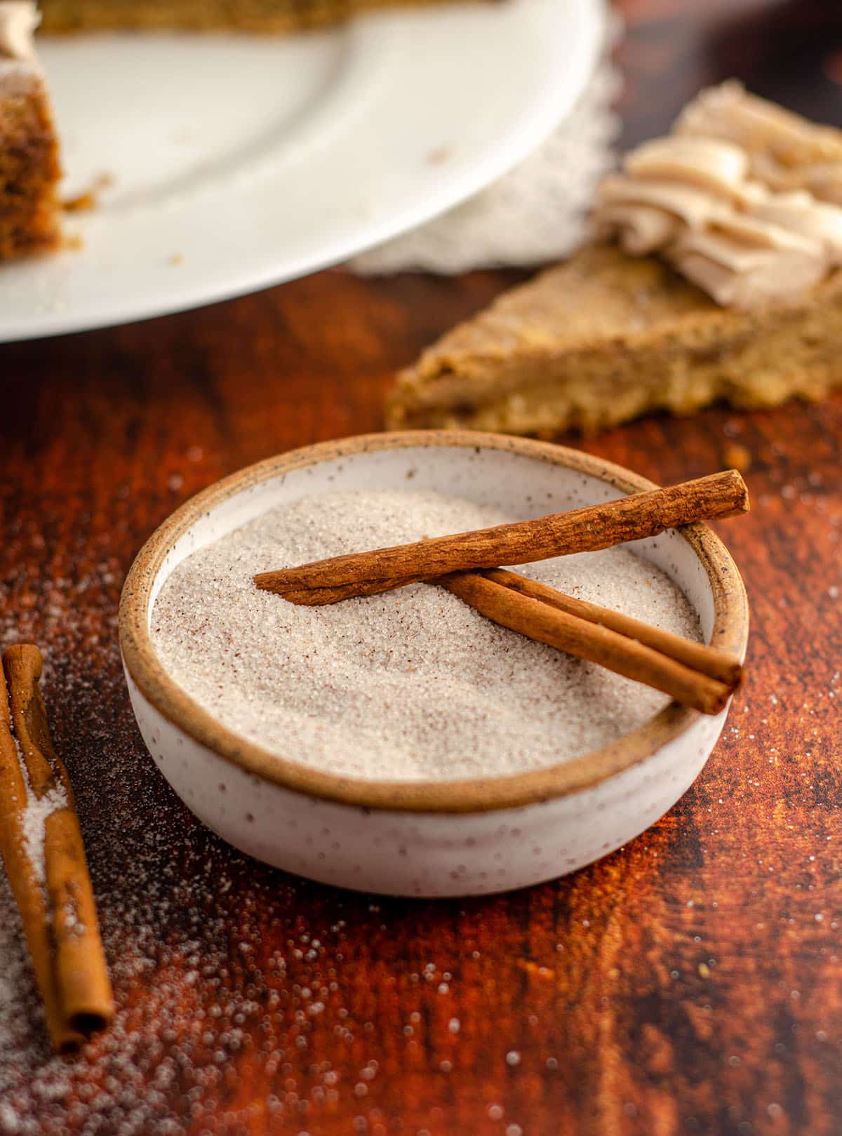 cinnamon and sugar and cinnamon sticks sitting in a ceramic bowl