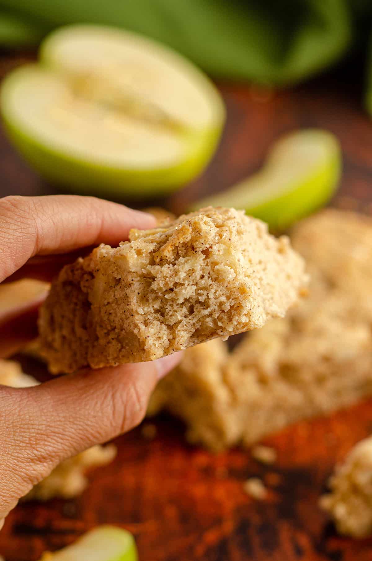 hand holding an apple scone with a bite taken out of it