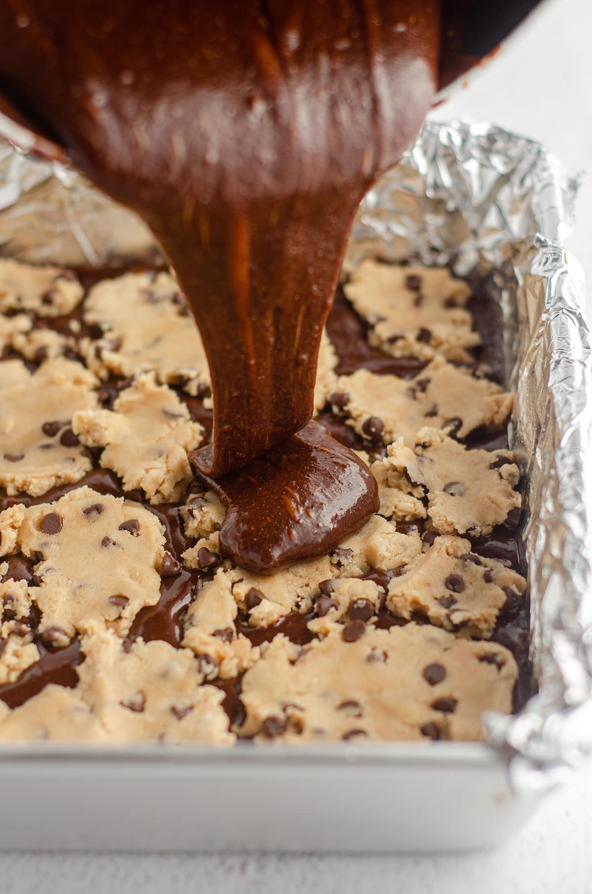 pouring brownie batter onto cookie dough layer