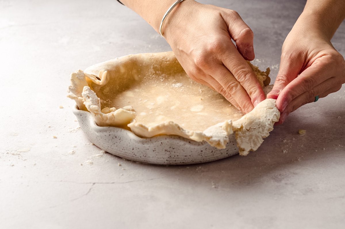 pressing a pie crust into a pie plate