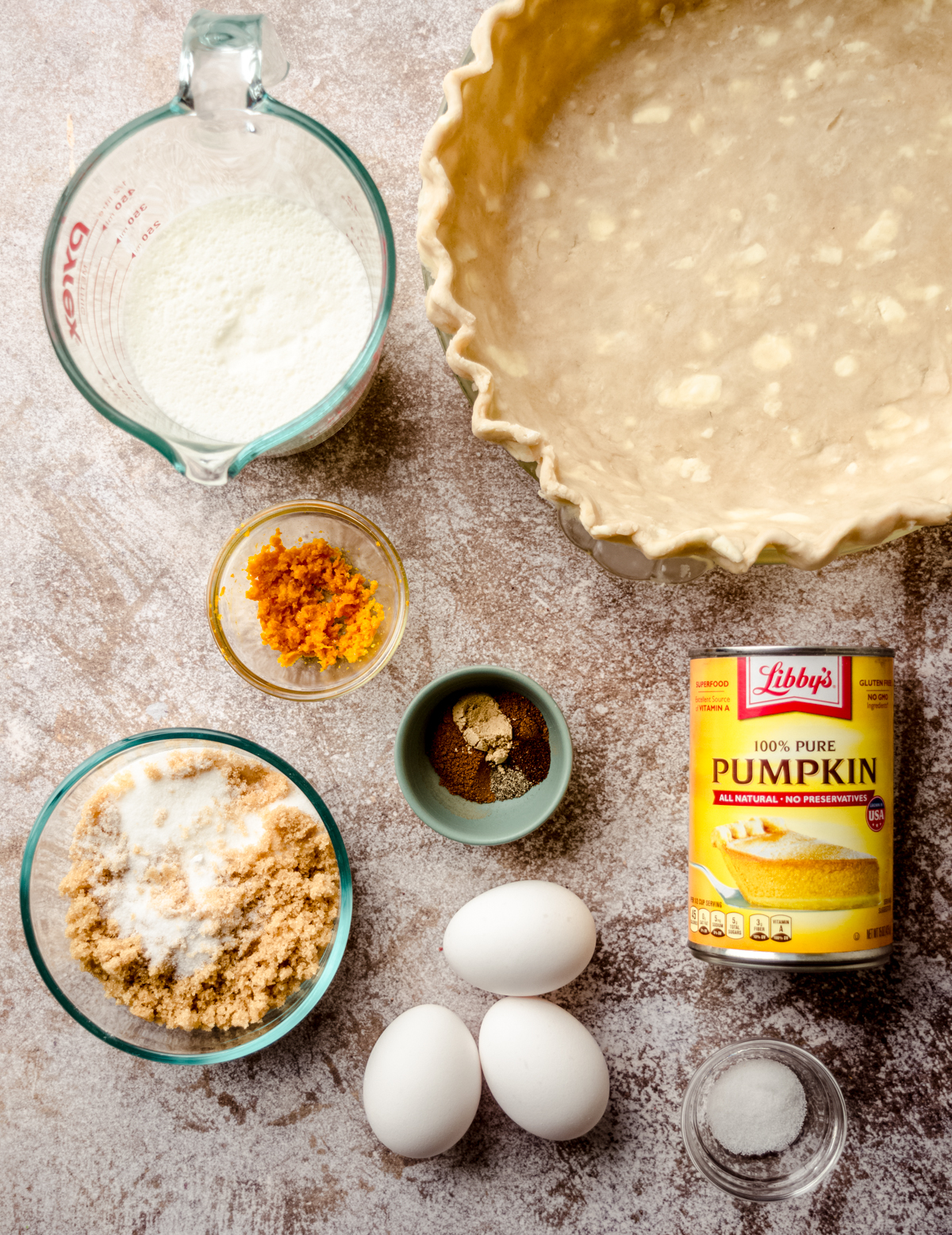 Aerial photo of ingredients to make pumpkin pie and a pie crust in a pie plate.