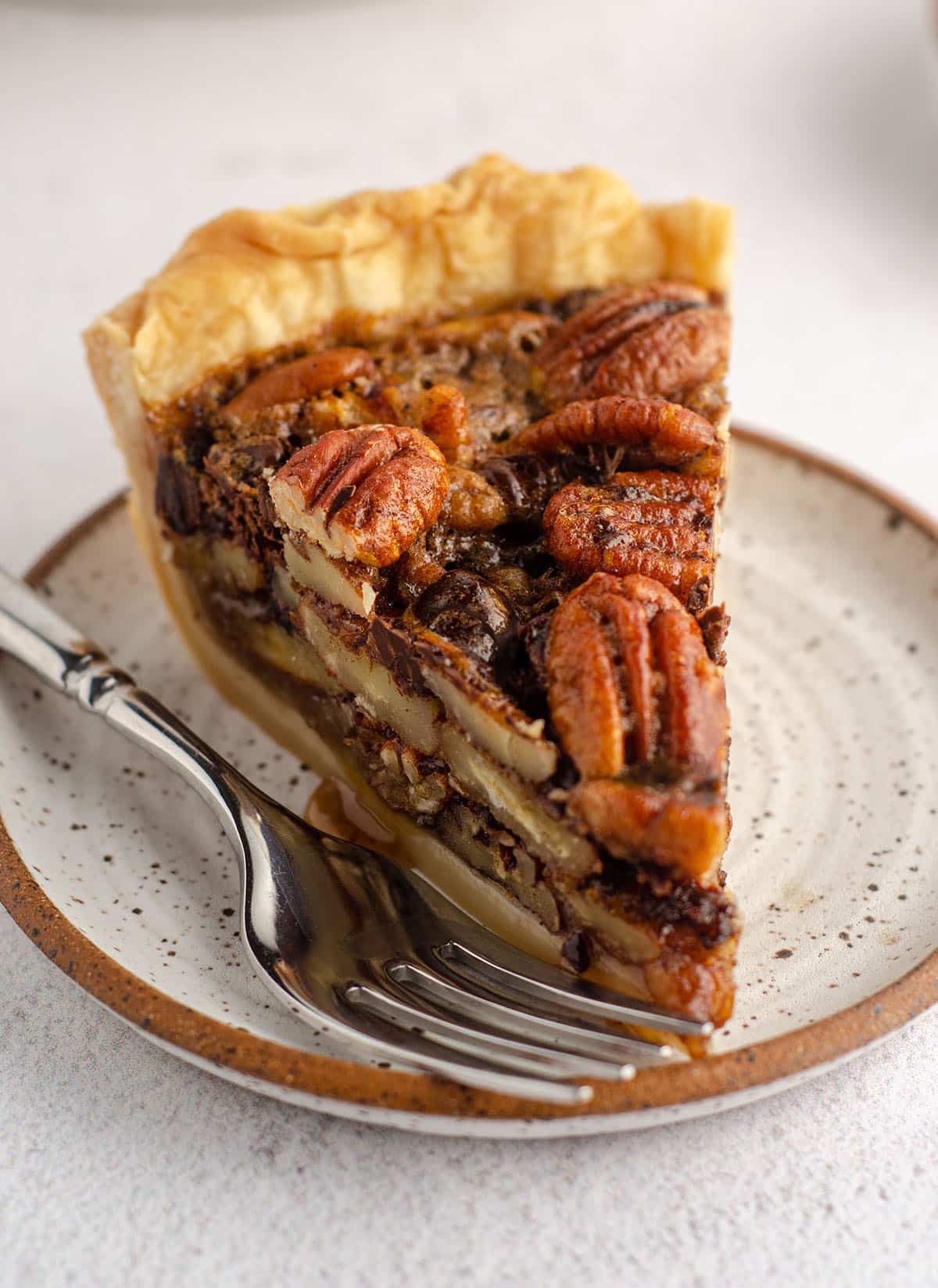 slice of chocolate chip pecan pie sitting on a plate with a fork