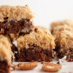 stack of german chocolate brownies with pecans and coconut scattered around