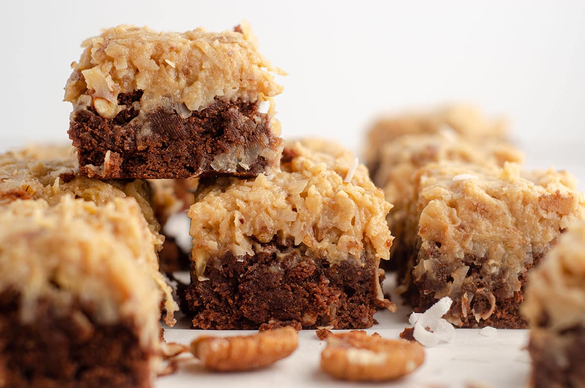 stack of german chocolate brownies with pecans and coconut scattered around