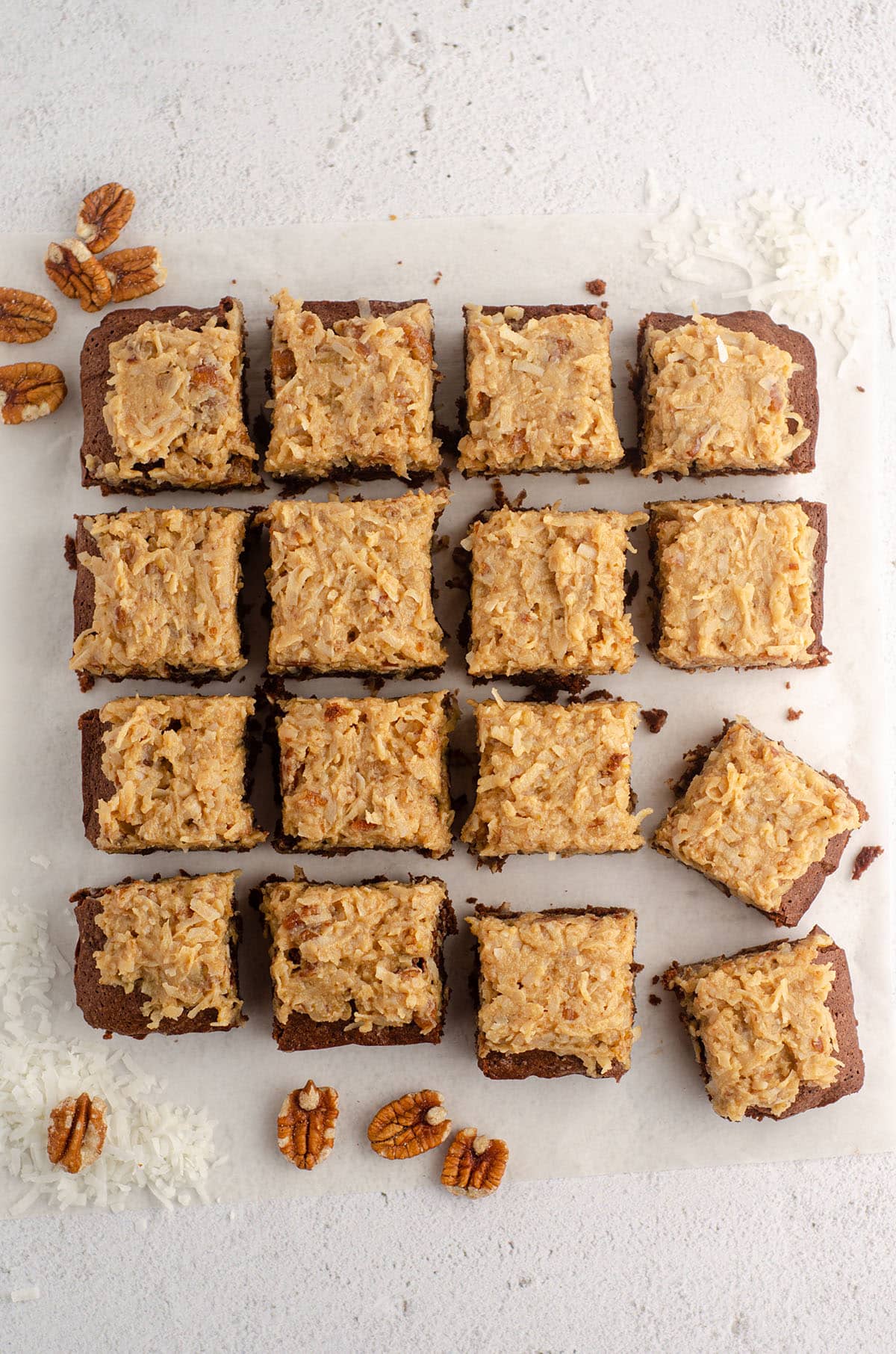aerial photo of german chocolate brownies cut into 16 bars and scattered around with pecans and shredded coconut
