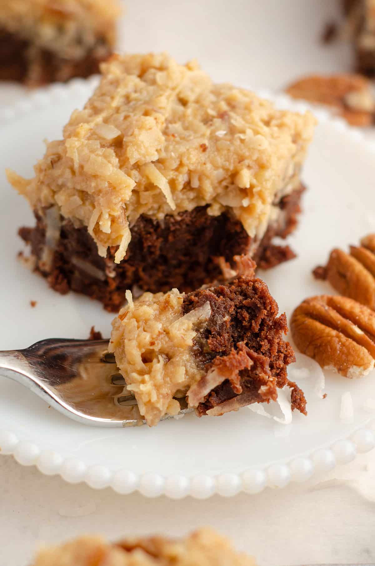 german chocolate brownie sitting on a plate with a fork full of a bite of the brownie