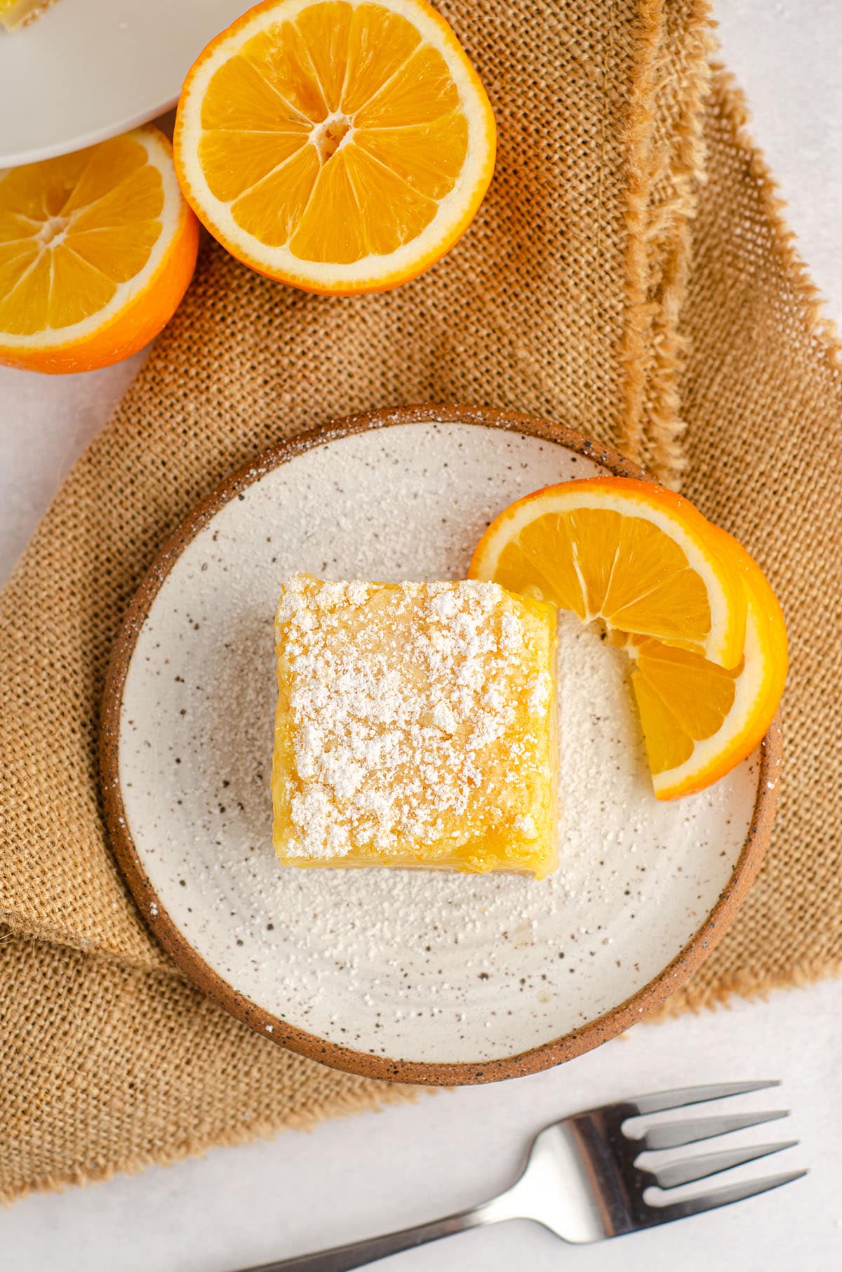 aerial photo of meyer lemon bar sitting on a plate with slices of meyer lemon