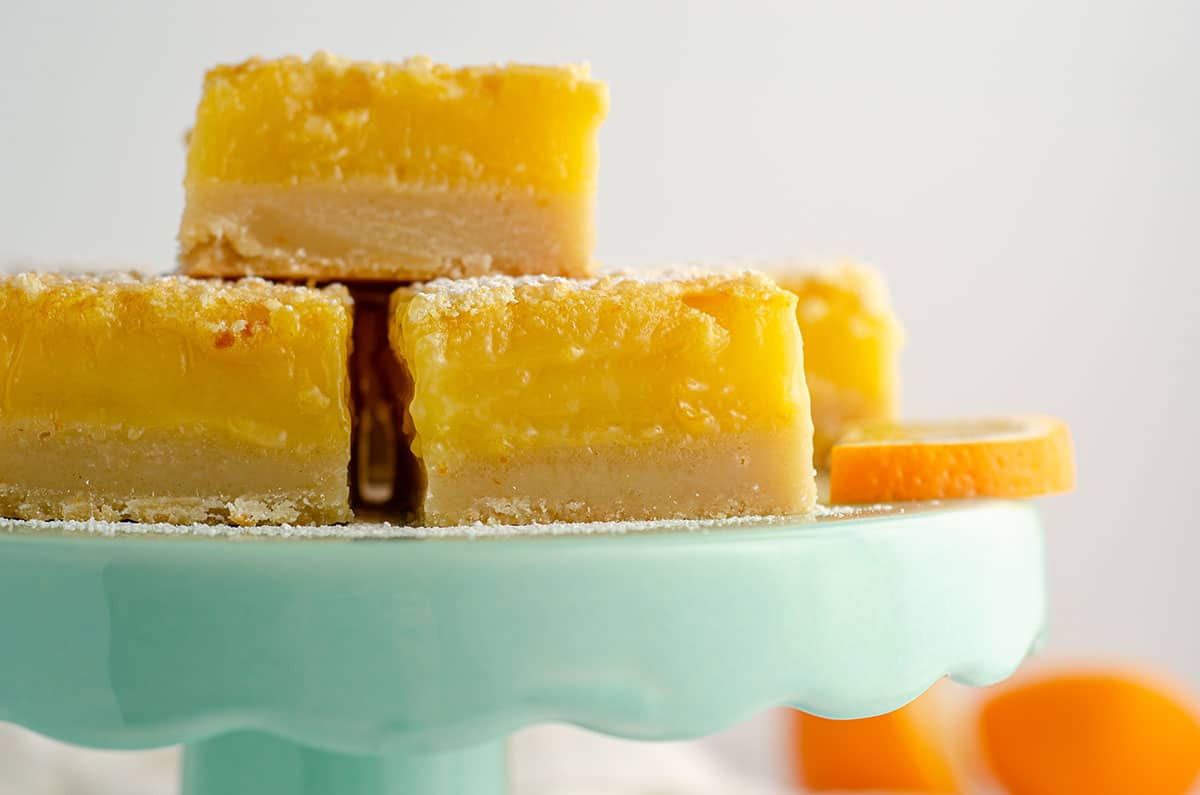 meyer lemon bars sitting on an aqua cake stand