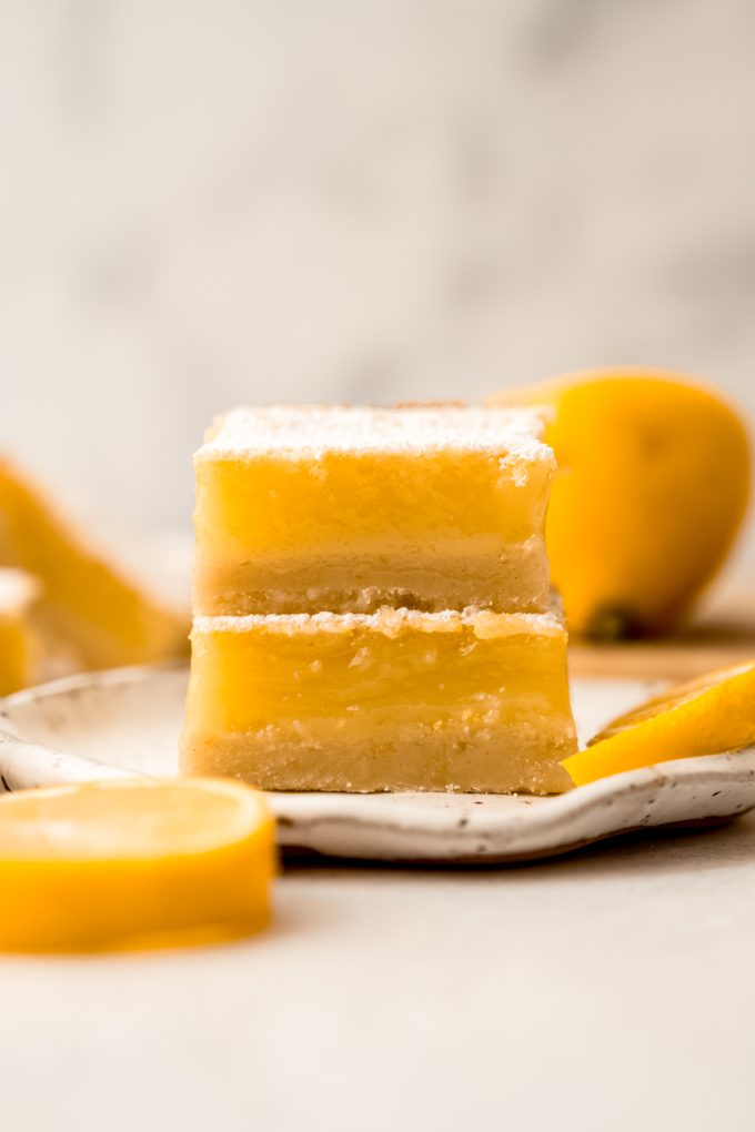 Two Meyer lemon bars stacked on a plate.