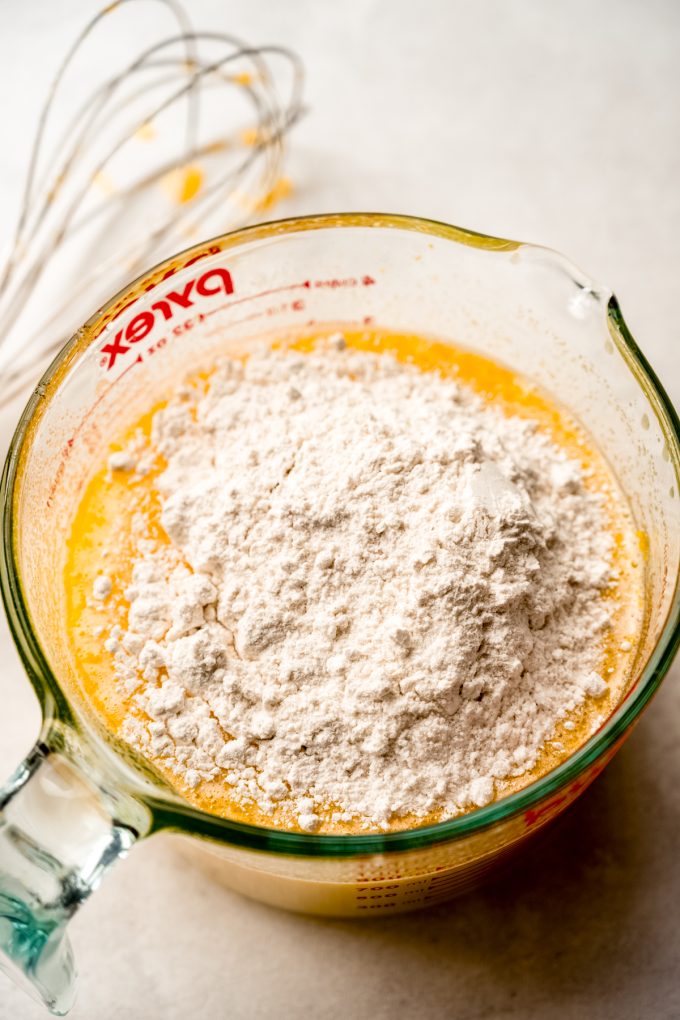 A large glass measuring cup filled with the filling mixture for Meyer lemon bars.
