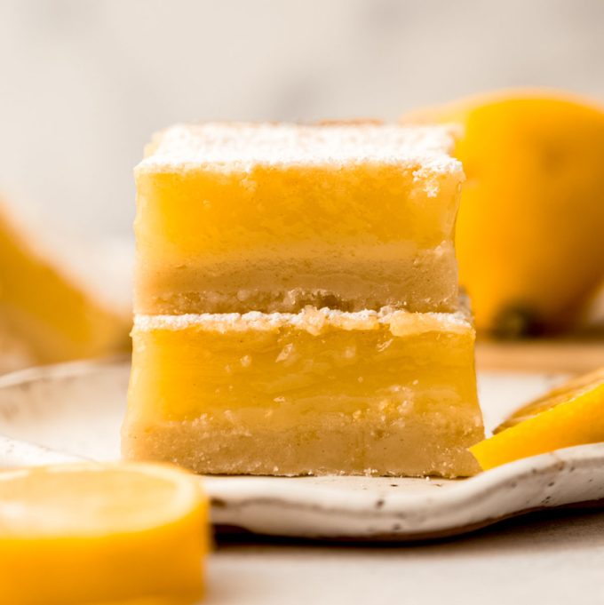 Two Meyer lemon bars stacked on a plate.
