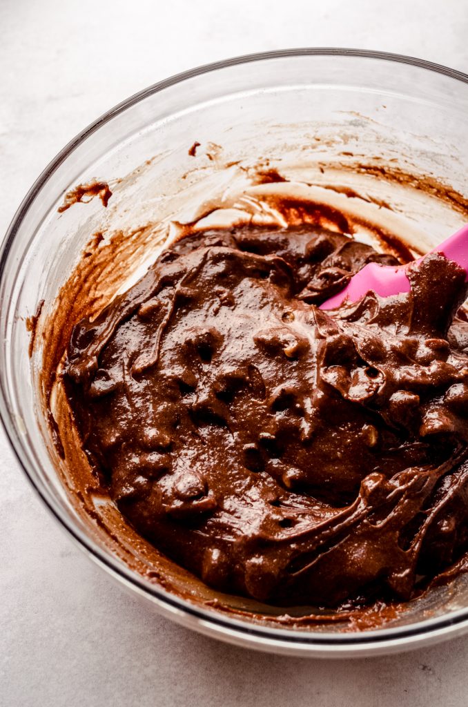 A bowl of brownie cookie dough with a pink spatula in it.