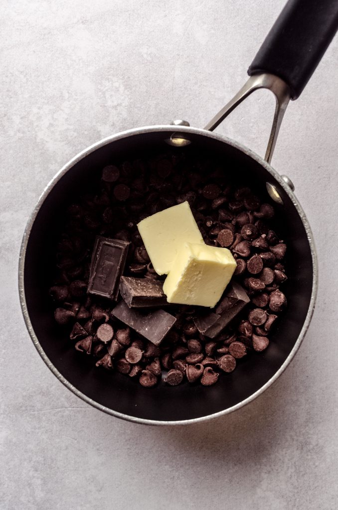 Aerial photo of a saucepan with chocolate chips, bar chocolate, and butter in it.