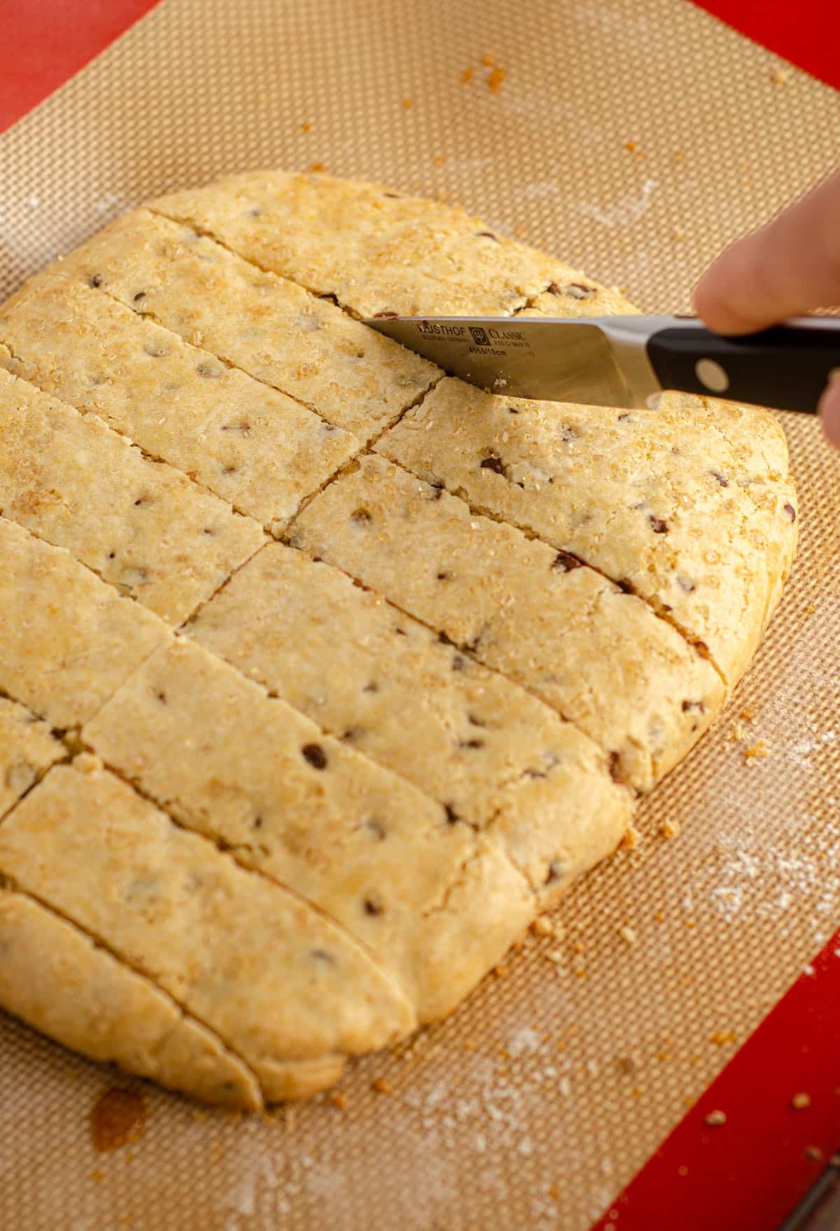 hand cutting biscotti slab into pieces to bake into individual biscotti