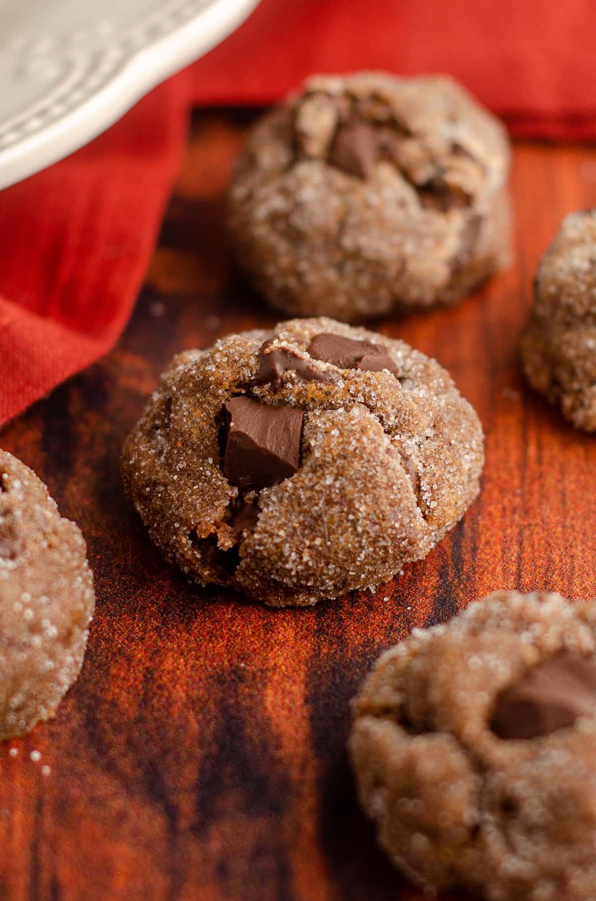 gingerbread chocolate cookie sitting on a wooden surface with burnt red kitchen towel behind it