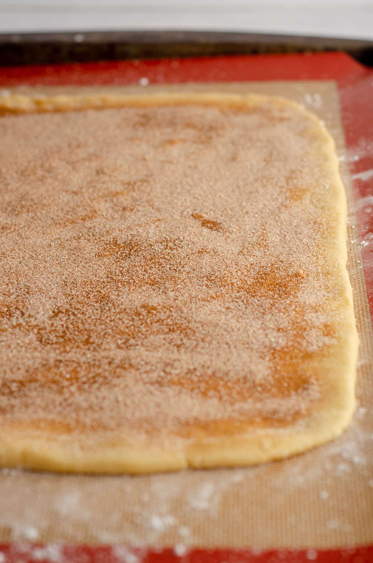 cinnamon pinwheel cookie dough sprinkled with cinnamon sugar ready to roll up into a log