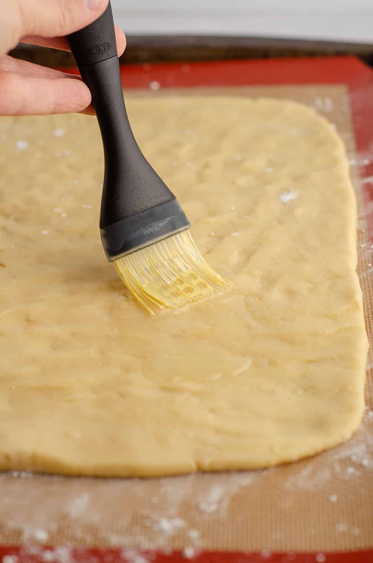 brushing an egg wash onto cinnamon pinwheel cookie dough