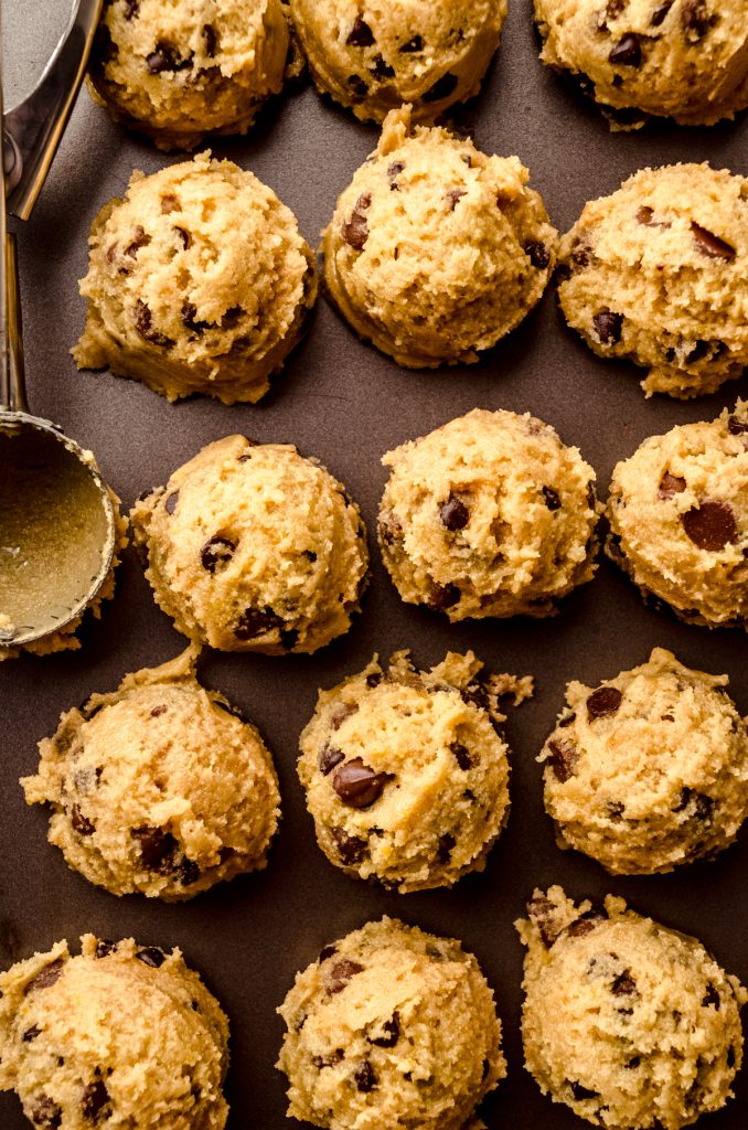 Balls of chocolate chip cookie dough on a surface.