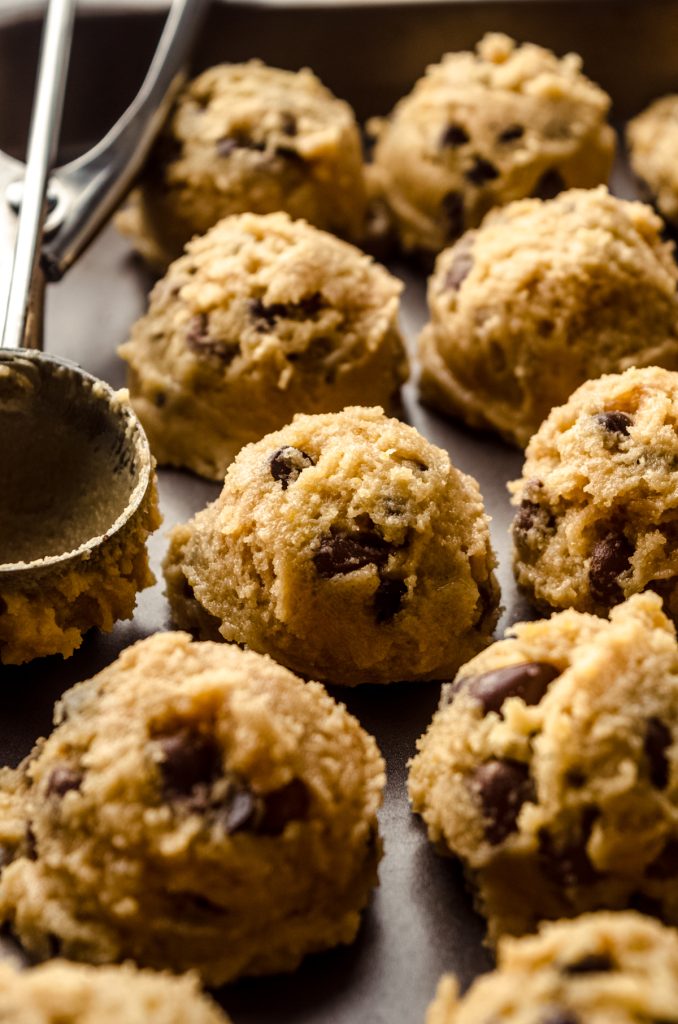 Balls of chocolate chip cookie dough on a surface.