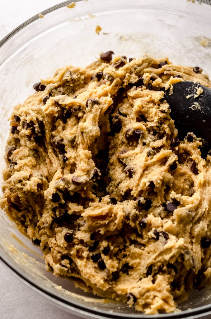 Chocolate chip cookie dough in a bowl with a spatula.