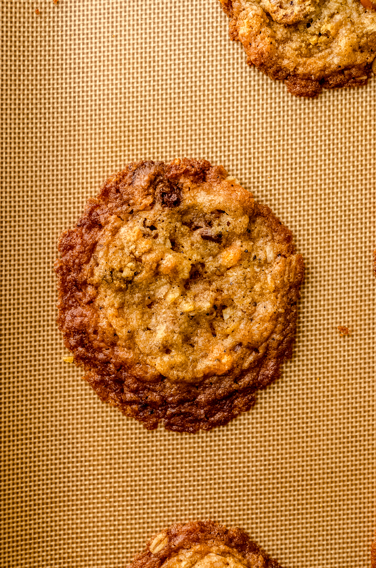 A compost cookie that has been baked on silicone which made it spread too much.