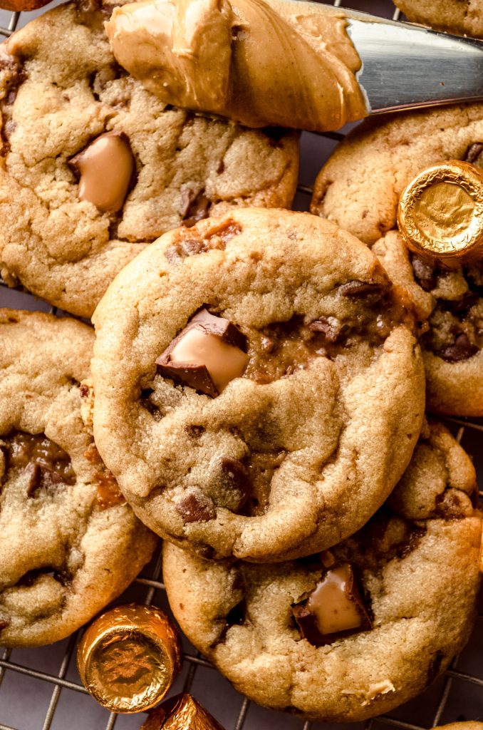 Peanut butter Rolo cookies on a surface with wrapped and unwrapped Rolos around them.