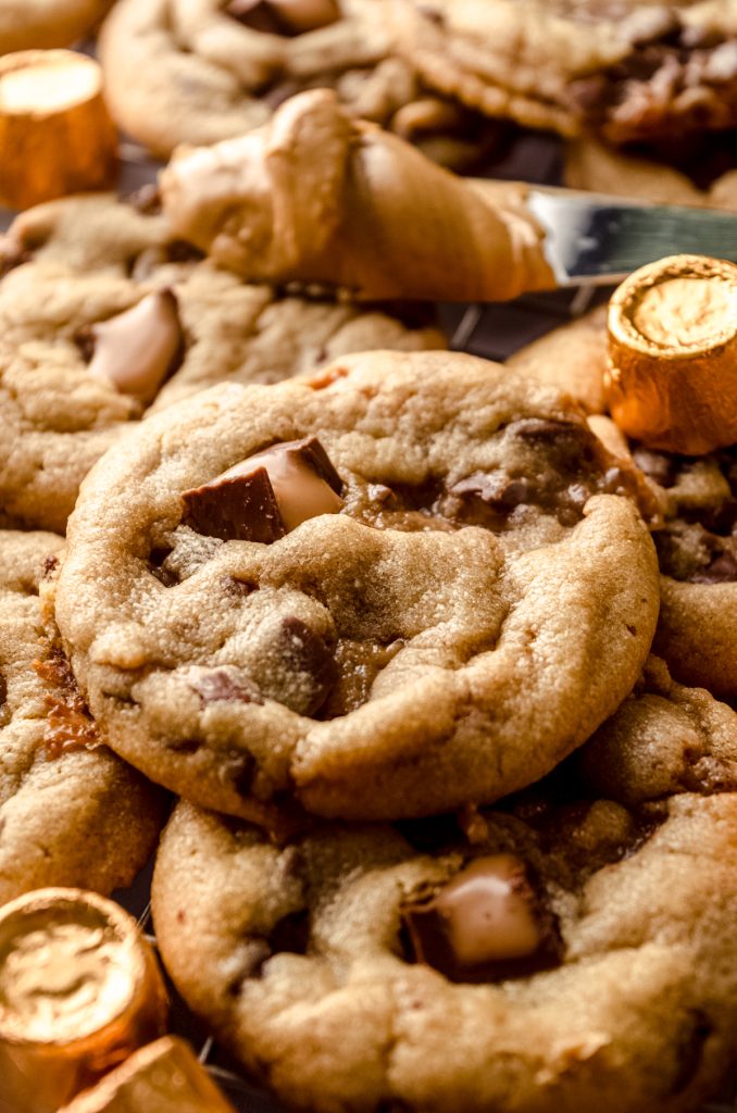 Peanut butter Rolo cookies on a surface with wrapped and unwrapped Rolos around them.