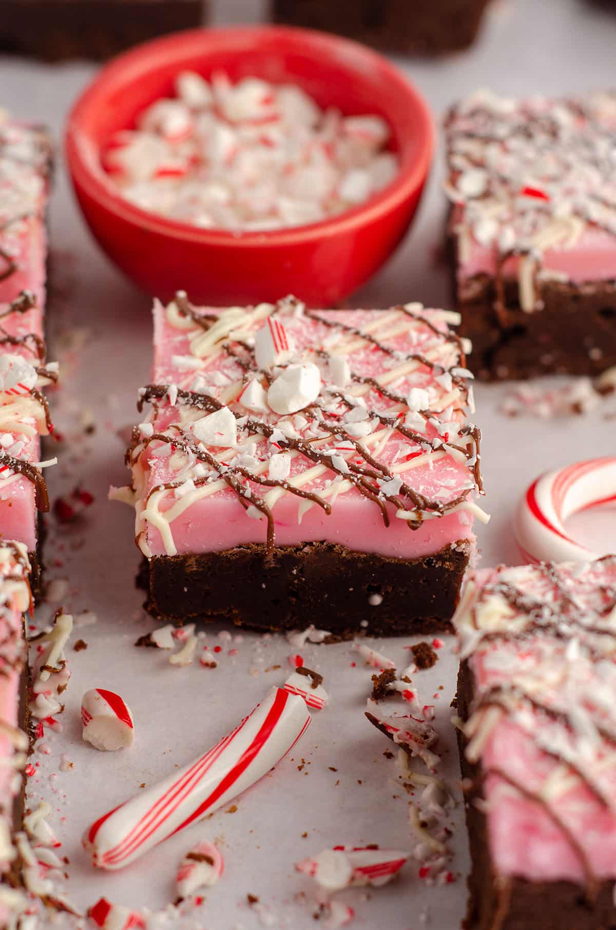 peppermint brownie sitting in front of a red prep bowl filled with crushed candy canes