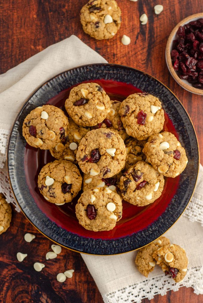 aerial photo of white chocolate cranberry oatmeal cookies sitting on a red and black plate