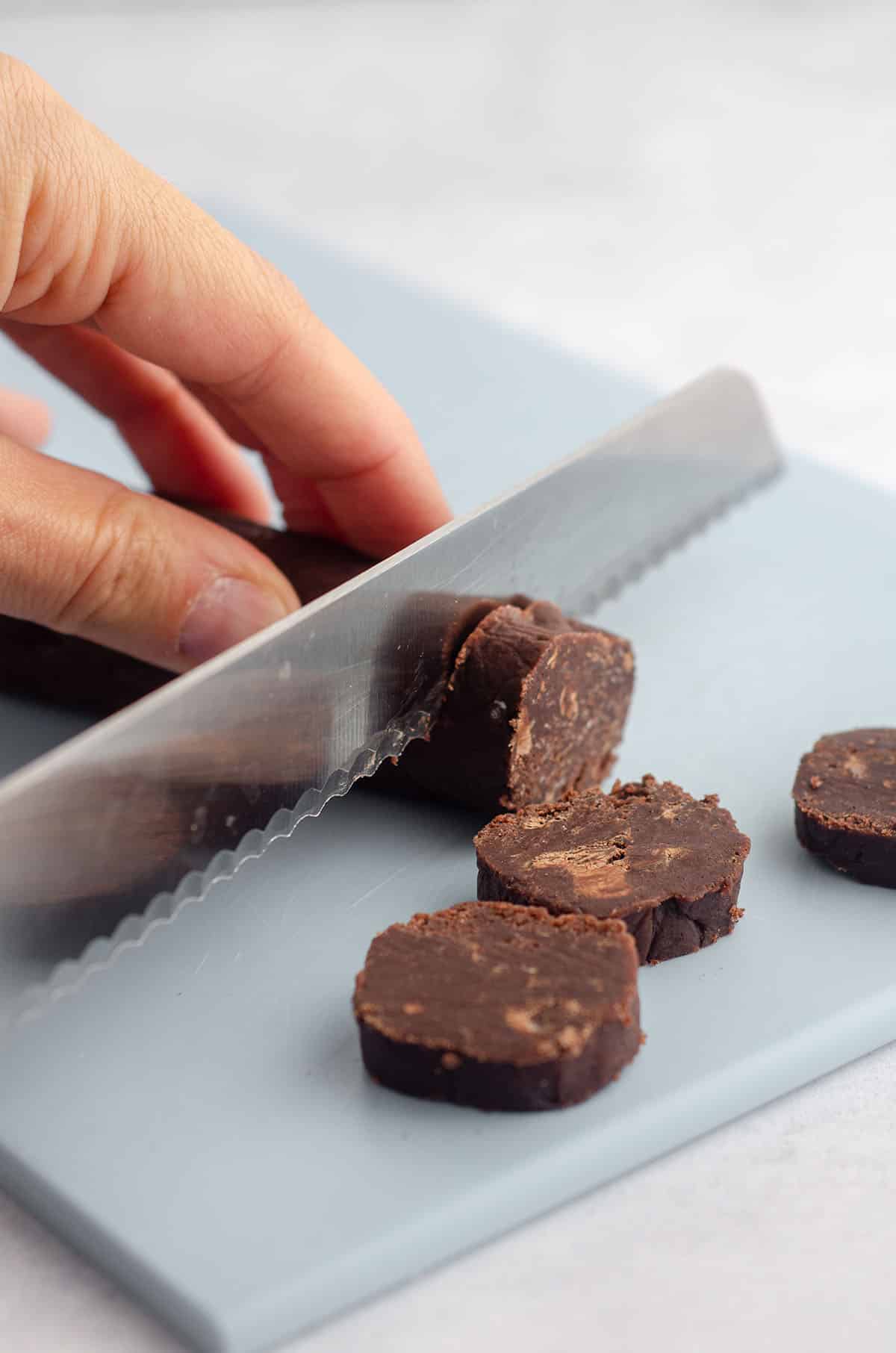 hand slicing a log of world peace cookies with a serrated knife