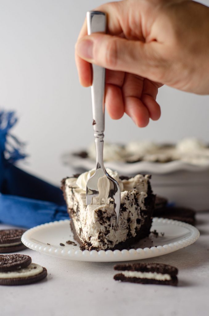 hand using a fork to dig into a slice of no bake oreo pie