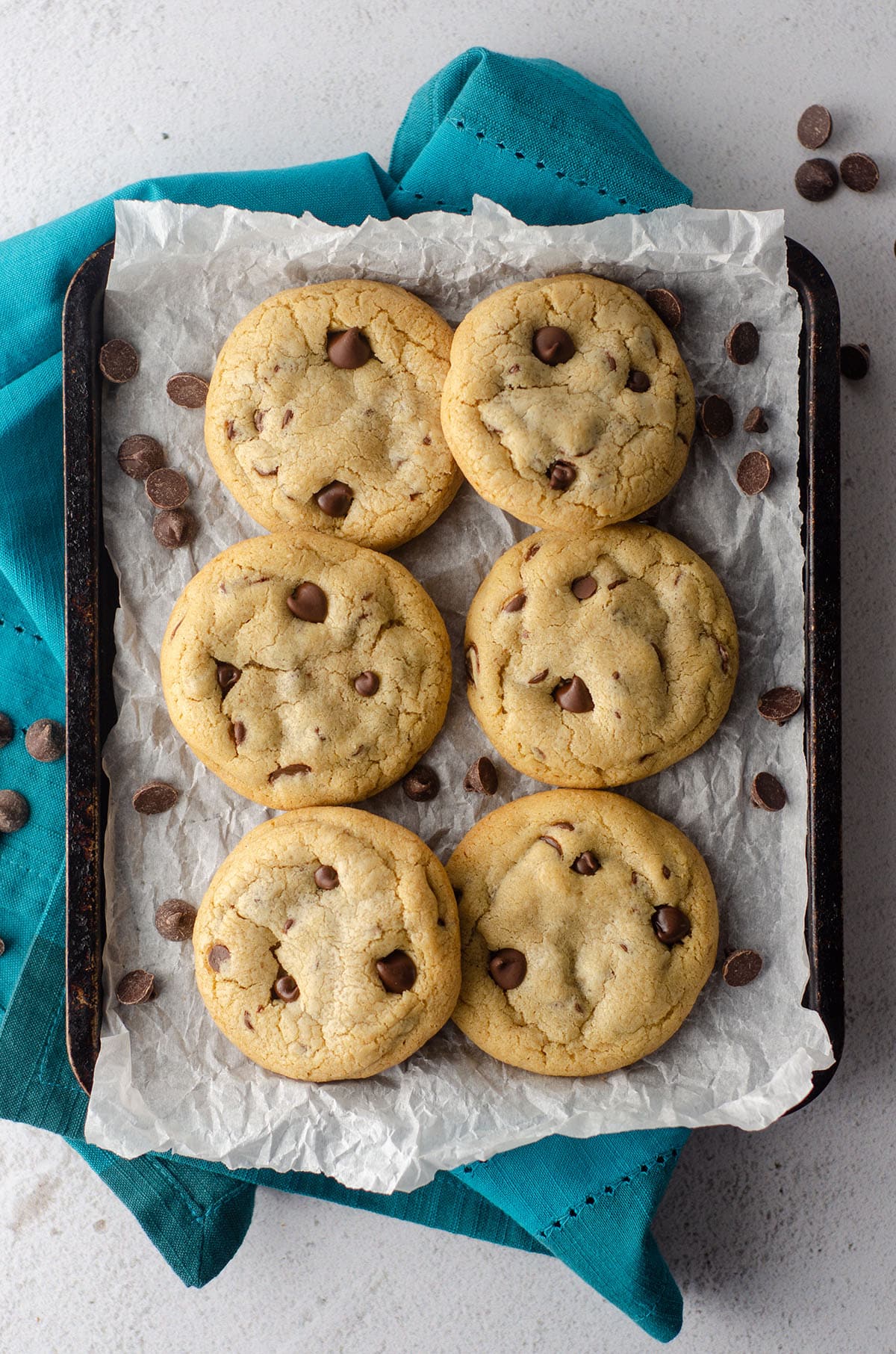 aerial photo of 6 small batch chocolate chip cookies sitting on parchment paper on a baking sheet