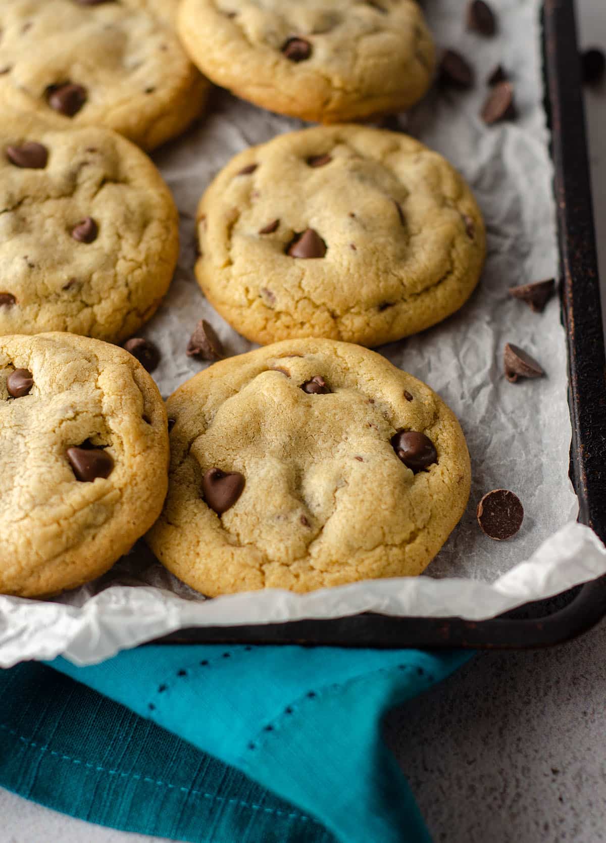 small batch of 6 chocolate chip cookies sitting on parchment paper on a baking sheet