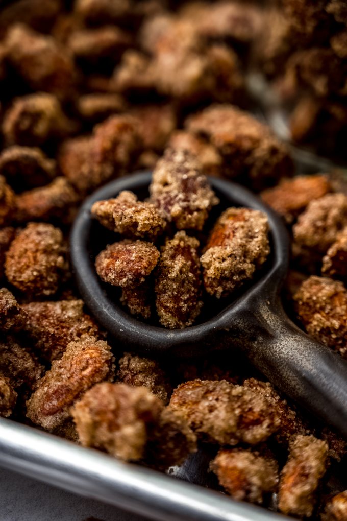 Aerial photo of a serving spoon scooping up candied almonds from a baking sheet.