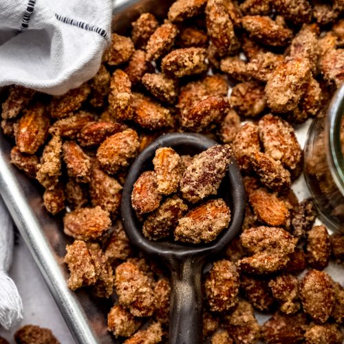 Aerial photo of a serving spoon scooping up candied almonds from a baking sheet.