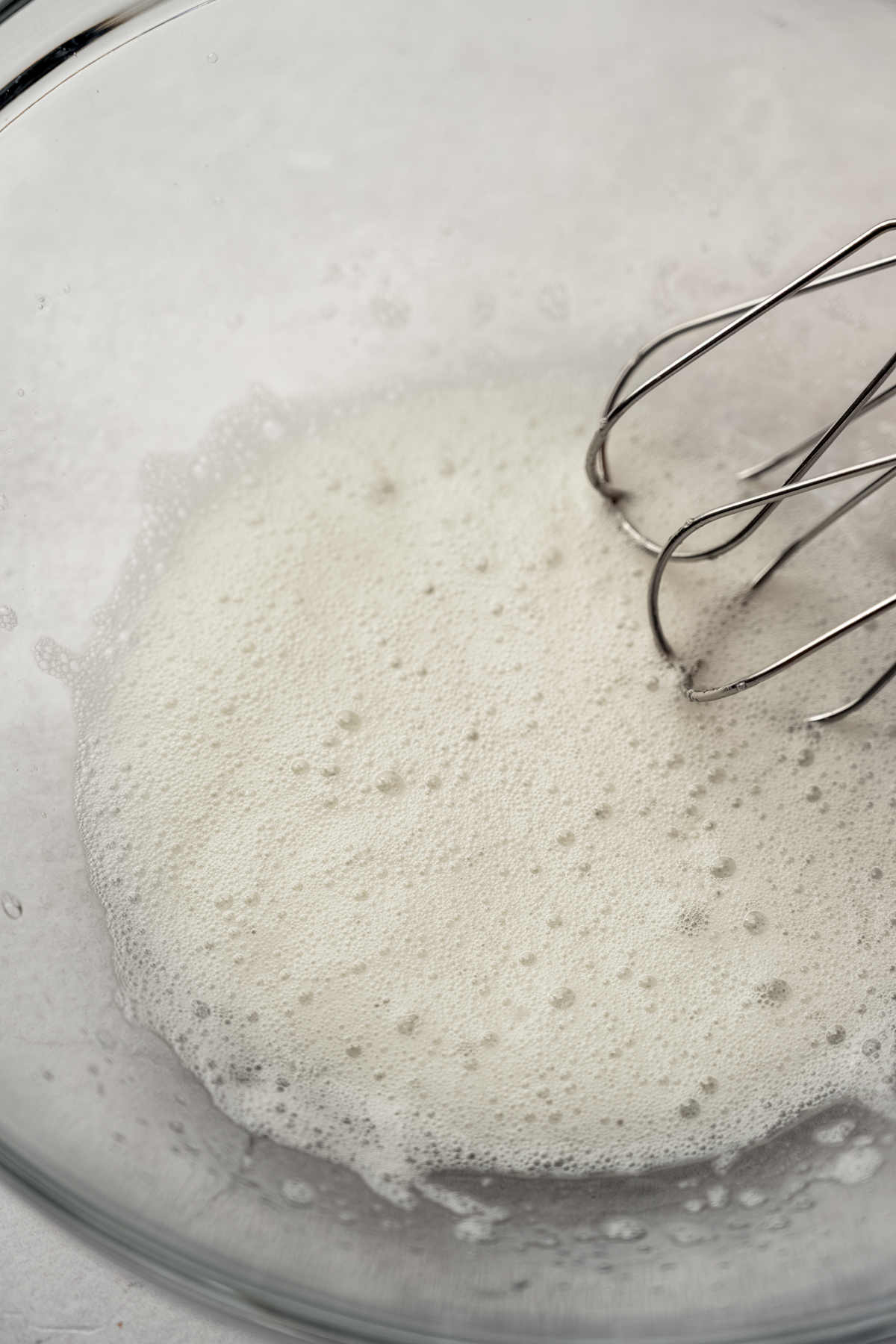 A bowl of whipped egg whites with electric beaters in it.