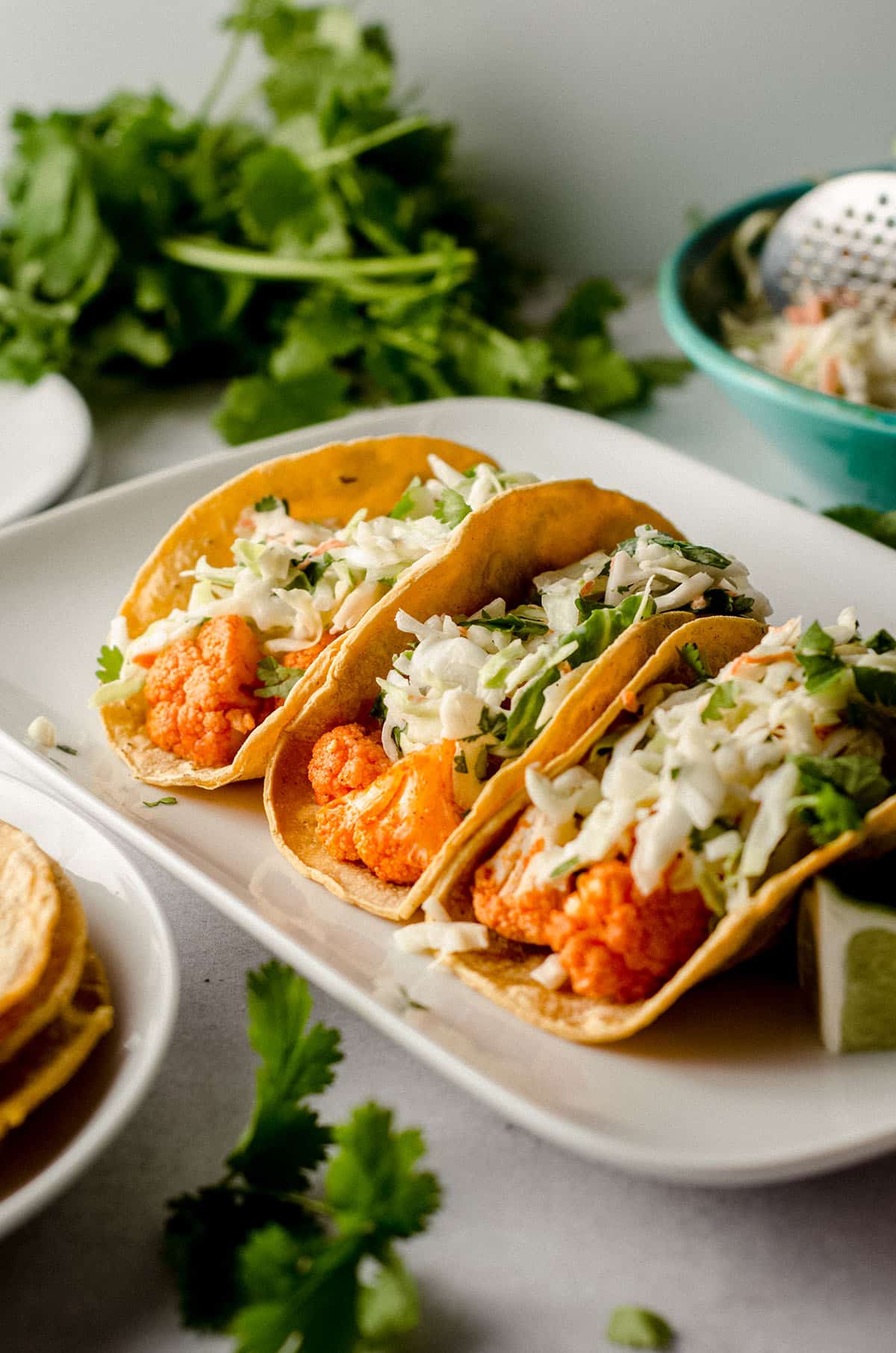 three buffalo cauliflower tacos sitting on a white platter