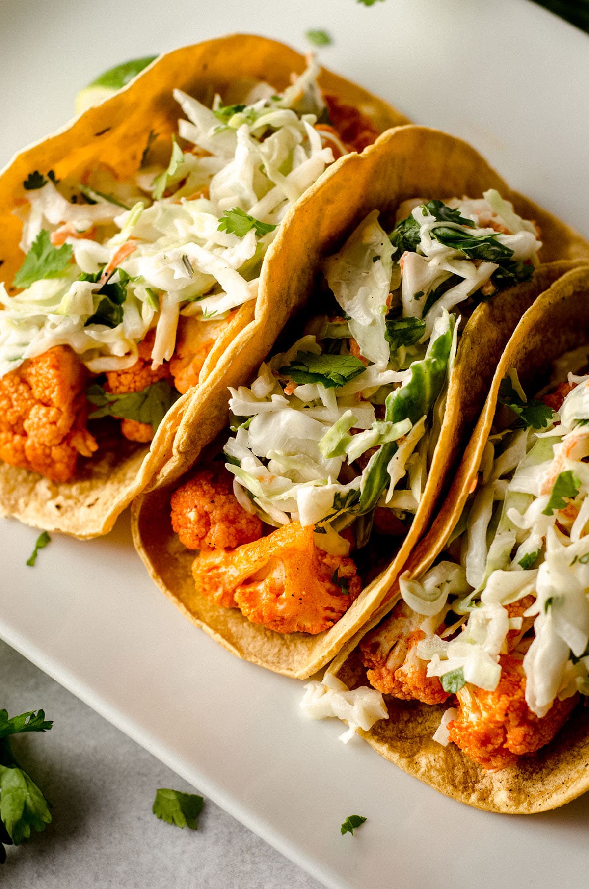 buffalo cauliflower tacos with cilantro slaw sitting on a white platter