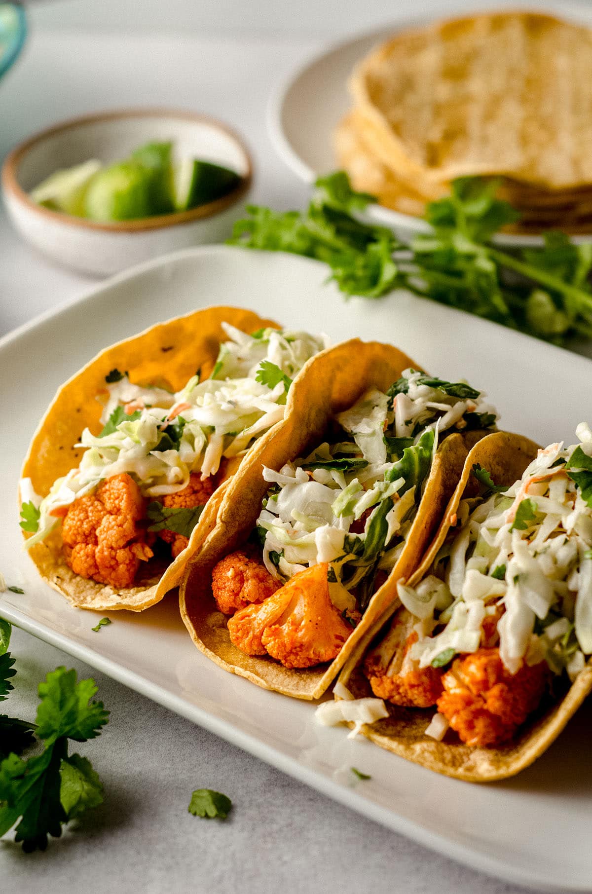 three buffalo cauliflower tacos sitting on a white platter