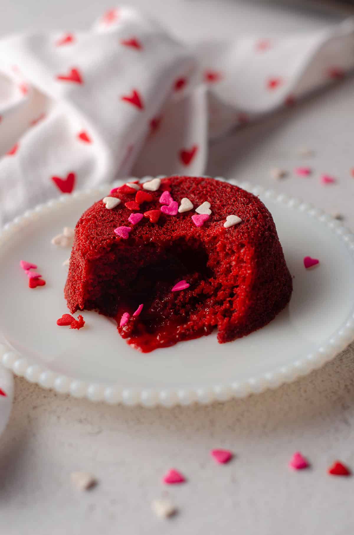 red velvet lava cake sitting on a white plate with heart sprinkles on top of it