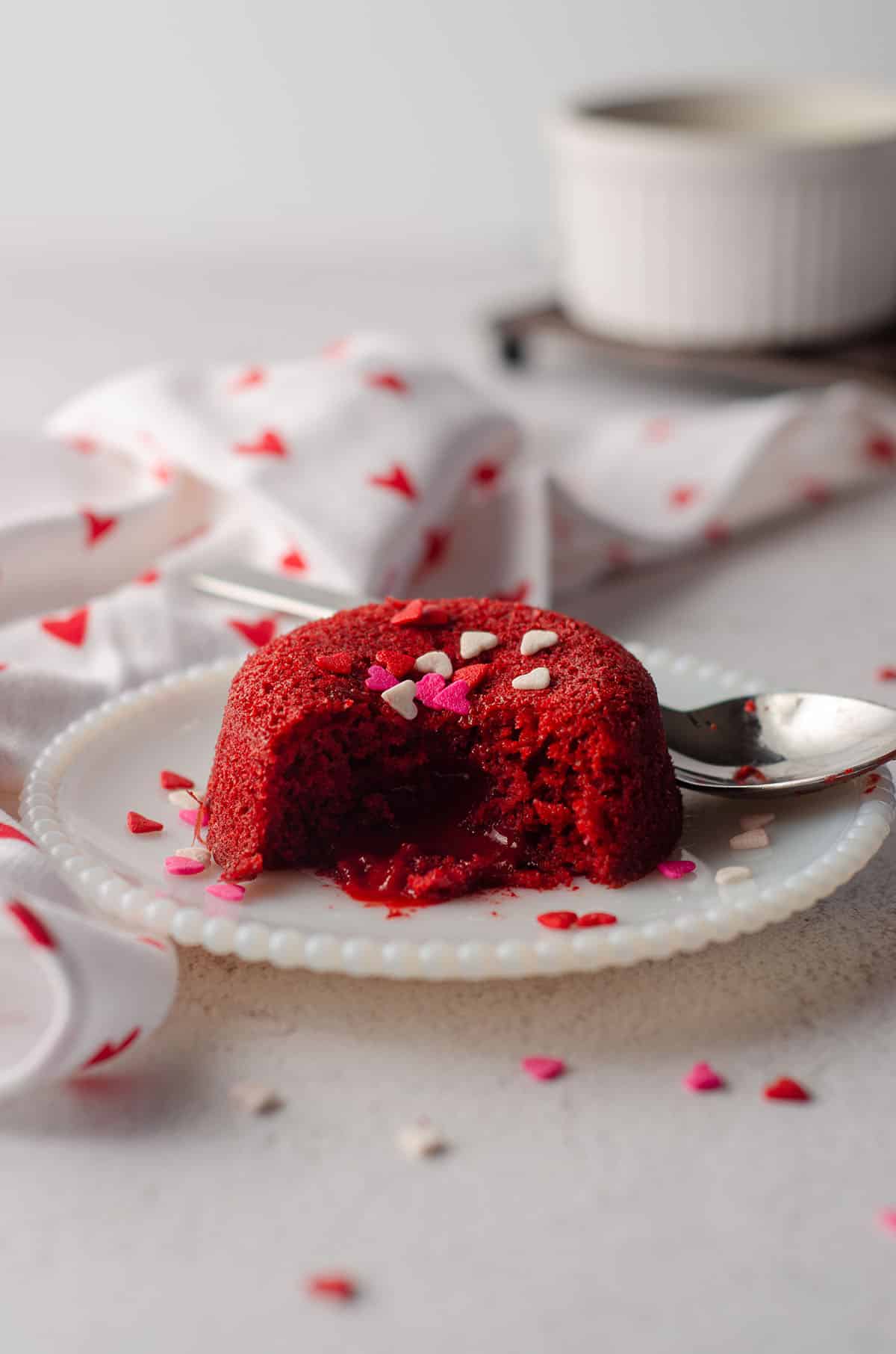 red velvet lava cake sitting on a white plate with heart sprinkles on top of it