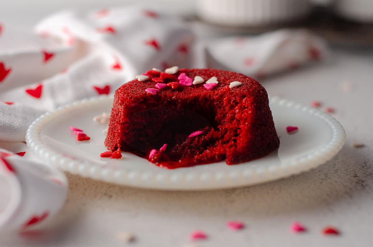 red velvet lava cake sitting on a white plate with heart sprinkles on top of it